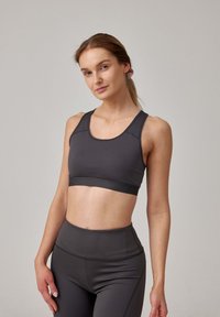 Donkergrijze sportieve crop top met een ronde halslijn, brede schouderbanden en naadloos ontwerp. Gecombineerd met bijpassende hoge taille legging.
