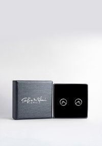 Silver vågformade örhängen i en svart sammetinläggning, visade i en texturerad grå låda med "Sofia Milani Jewels"-logotyp.