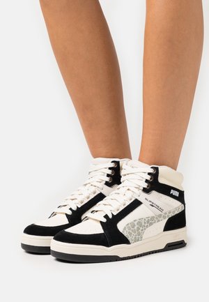 Baskets montantes en cuir blanc et daim noir, avec un accent en imprimé léopard. Lacets, col rembourré et semelle texturée.