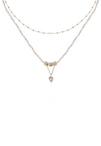 Collier en couches dorées et argentées avec des perles facettées, un élément décoratif central et un pendentif en forme de goutte avec une pierre transparente.