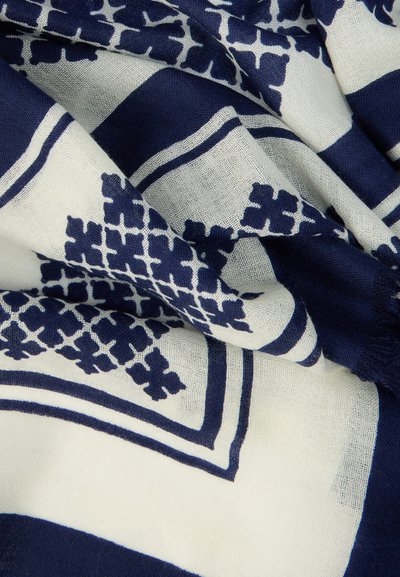 Écharpe aux motifs bleu marine et blanc en tissu léger, présentant des designs géométriques et des bords légèrement effilochés.