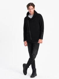 Sort lynlåsjakke med bred krave, parret med slidte sorte jeans og sorte højtopstøbte støvler. Glat stof, moderne design.