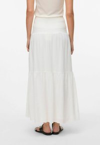 Jupe maxi blanche faite en tissu léger avec une taille smockée et un design à volants. Présente une silhouette fluide et une finition unie.