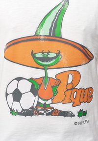 Hvid t-shirt med en tegneseriefigur iført en orange sombrero og jersey, stående ved siden af en fodbold, med grønne accenter og teksten "Pique."