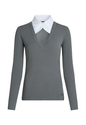Maglione grigio a coste con maniche lunghe e scollo a V profondo, indossato sopra una camicia bianca con colletto appuntito, con piccolo dettaglio ricamato vicino all’orlo.