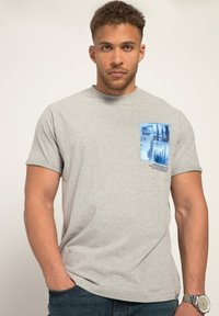 Camiseta de algodón gris con un estampado gráfico azul en el lado izquierdo del pecho que incluye el texto "UTOPIA" y otras imágenes azules. Mangas cortas, cuello redondo.