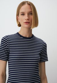 Marineblaues geripptes T-Shirt mit weißen horizontalen Streifen, kurzen Ärmeln und rundem Halsausschnitt. Glatte Textur, figurbetontes Design.