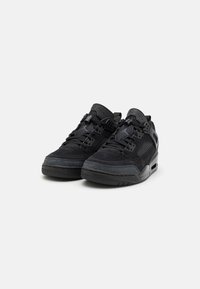 Black sneakers with a mix of smooth and textured materials, featuring a low profile, lace-up design, mesh accents, and a contrasting sole.