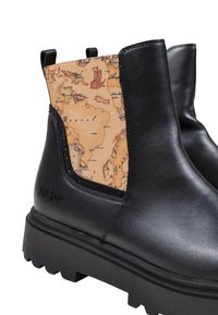 Botas de cuero negras hasta el tobillo con un panel elástico marrón estampado que presenta un mapa vintage. Suela de goma negra gruesa con detalle texturizado.