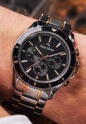 Montre bracelet bicolore argent et or avec un cadran noir, des sous-cadrans chronographe, de grands index horaires et un bracelet en acier inoxydable.