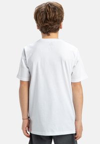 Vit bomull t-shirt med korta ärmar och rund hals, sedd från baksidan. Slät textur, enkel design, inga synliga logotyper eller mönster.