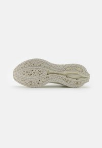 Shoe sole in light beige rubber, featuring intricate geometric patterns. Flexible structure with a wavy shape and textured surface.