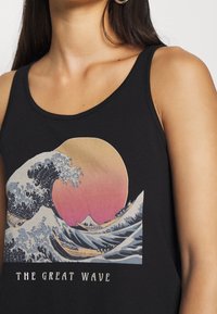 Canotta nera con una grafica colorata di un'onda e del sole, con il testo "THE GREAT WAVE" in un font a contrasto nella parte inferiore.