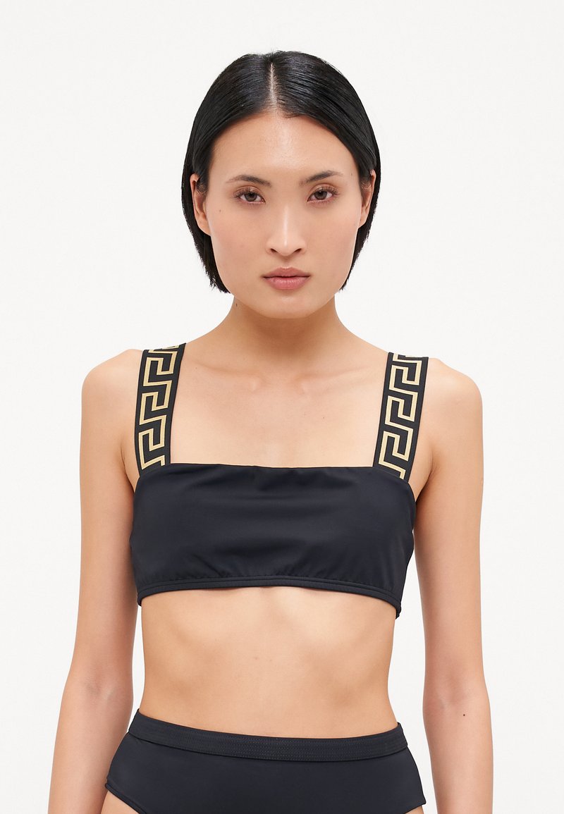 Czarny skórzany bikini top z szerokimi ramiączkami zdobionymi złotym geometrycznym wzorem. Gładki materiał i prosty dekolt tworzą minimalistyczny design.