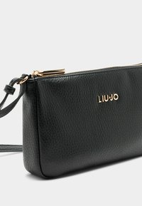 Borsa a mano in pelle nera con superficie testurizzata, hardware dorato, chiusura a zip e tracolla removibile. Caratterizzata dal marchio in rilievo "LIU-JO."