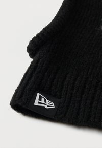 Μαύρο πλεκτό σκουφάκι με ανάγλυφη ραφή. Διαθέτει ραμμένη μαύρη υφασμάτινη ετικέτα με λευκό λογότυπο. Μαλακό υλικό, σχεδιασμένο για ζεστασιά.