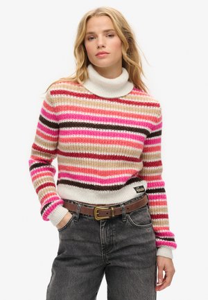 Gestreepte trui in roze, beige en bruine tinten; heeft een hoge, ribbelige kraag en ribbelige manchetten; gedragen boven hoge taille jeans met een riem.