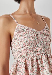 Blomsterkjole med lyserøde og grønne mønstre, smocket bodice, tynde stropper og en udvidet nederdel. Blødt stof med let tekstur.