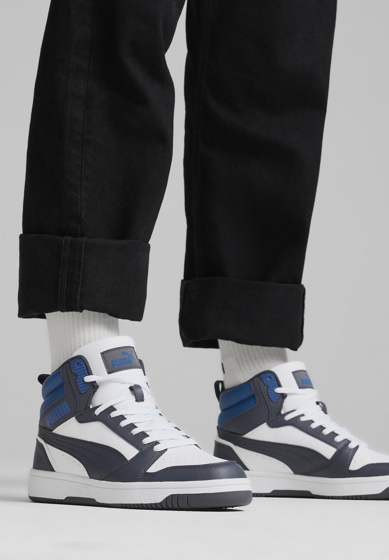 Zapatillas altas con una combinación de colores blanca, navy y azul. Materiales de cuero y sintético, puntera perforada, collar acolchado y suela de goma.