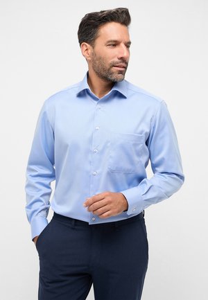 Hellblaues Hemd mit Knopfverschluss und einer Tasche; aus einem glatten Stoff gefertigt. Die langen Ärmel besitzen eine Knopfmanschette und werden von einem eleganten Kragenentwurf ergänzt.