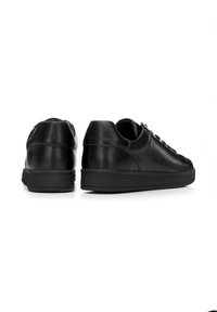 Sneaker in pelle nera con punta arrotondata, design con lacci piatti, suola testurizzata e silhouette minimalista.