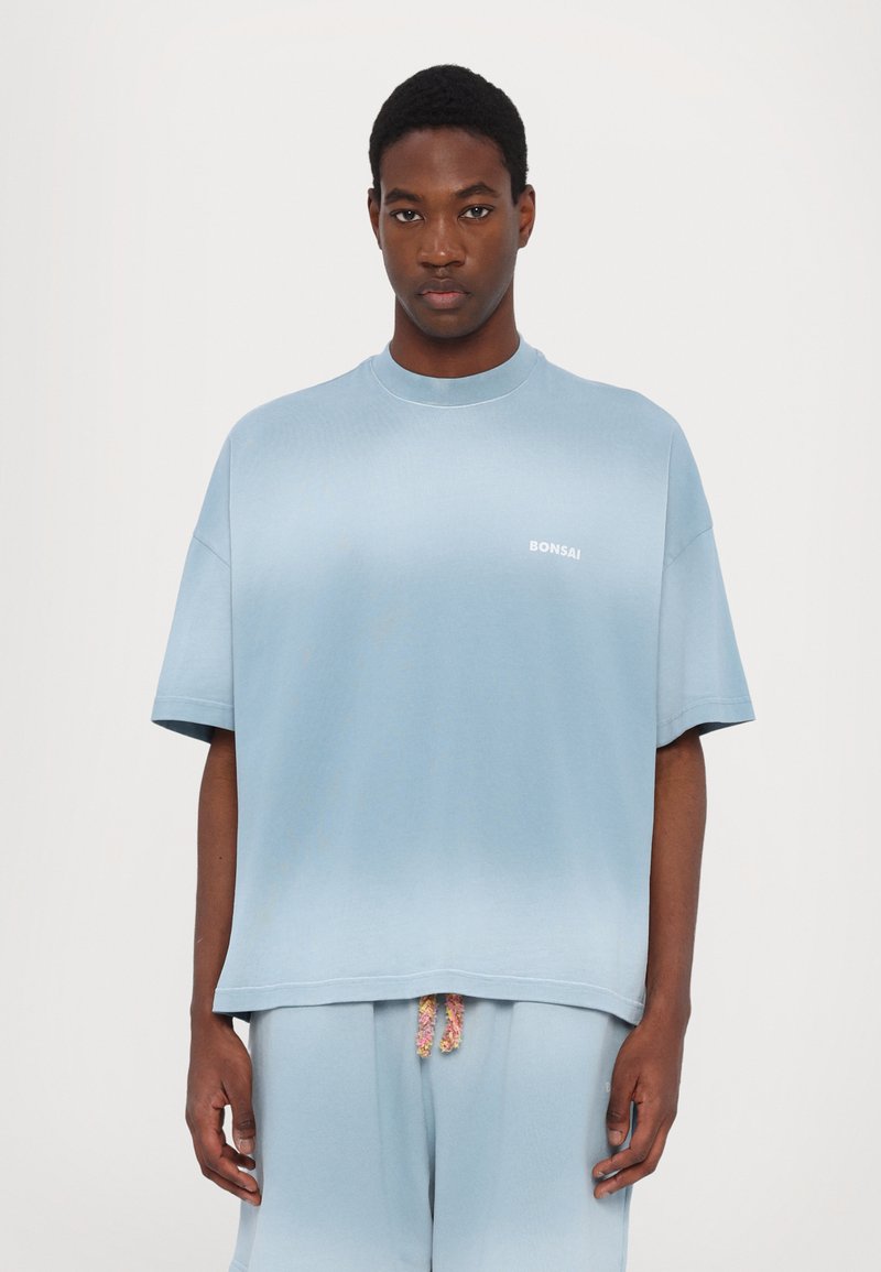 Himmelblaues, übergroßes T-Shirt aus Baumwollmischung mit rundem Ausschnitt und kurzen Ärmeln; verfügt über ein weißes Logo auf der Brust.