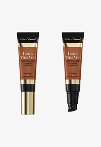 Deux tubes de fond de teint, marron avec des accents dorés. L'un a un embout à pompe ; l'autre a un capuchon à vis. Tous deux étiquetés "Born This Way Soft Matte."