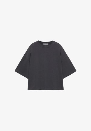 Szürke pamut póló laza szabással, széles rövid ujjakkal és lekerekített nyakkivágással. Egyenes alsó szegély és minimális varrásdíszítéssel rendelkezik.