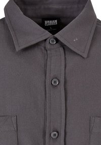 Szara koszula na guziki wykonana z tkaniny o splocie. Posiada kołnierzyk, przednią listwę z guzikami oraz jedną kieszeń na piersi.