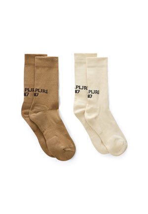 Zwei Paar gerippte Knöchelsocken, eines braun und eines cremefarben, jeweils mit schwarzem Text mit der Aufschrift "PLJR 87" nahe dem oberen Bündchen.