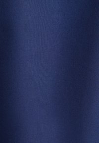 Ciemnoniebieska tkanina o drobno tkanej fakturze i subtelnych skośnych fałdach tworzących delikatne cienie.