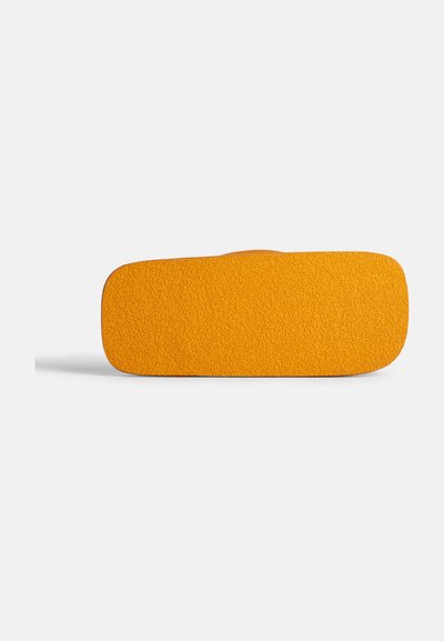 Oranssi suorakulmainen matto, jossa on teksturoidun pinnan, pyöristetyt kulmat ja tasainen pohja. Yksinkertainen muotoilu, ei näkyviä kuvioita tai kiinnikkeitä.
