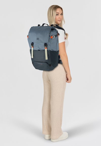 Mochila de tejido azul y marino con acentos en naranja y beige, que presenta correas ajustables y un asa superior para llevar.