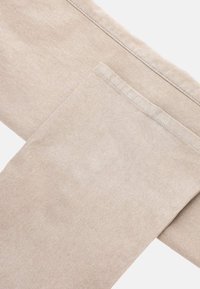 Pantaloni in tessuto beige caratterizzati da una texture liscia, design a gamba dritta e orli rifiniti con cura. Nessun motivo visibile o dettagli in metallo.