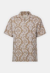 Camicia a maniche corte beige con motivo floreale bianco, caratterizzata da una chiusura con bottoni, colletto e una texture di tessuto leggero.