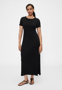 Czarna, maxi sukienka z krótkim rękawem wykonana z miękkiego materiału, z okrągłym dekoltem i bocznym rozcięciem. W połączeniu z prostymi czarnymi sandałami.