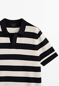Polo à rayures en marine et crème, avec un col, des manches courtes et un tissu tricoté texturé. Accents contrastants subtils.