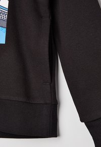 Černá mikina s žebrovanými manžetami a lemem, s kapsou na boku a modrou grafikou na přední straně. Měkká bavlněná látka.