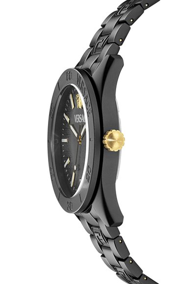 Svart armbandsur med en strukturerad svart urtavla, gyllene accenter och graverad bezel. Har ett mönstrat metallarmband och en rund klockkropp med en krona.
