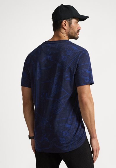 T-shirt azul-marinho de manga curta com um design de desenhos técnicos em azul mais claro. Decote redondo, corte descontraído e bainha reta.