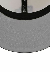 Casquette grise et noire avec une visiblité de couture et une étiquette « 9FIFTY » sur la bande intérieure noire.