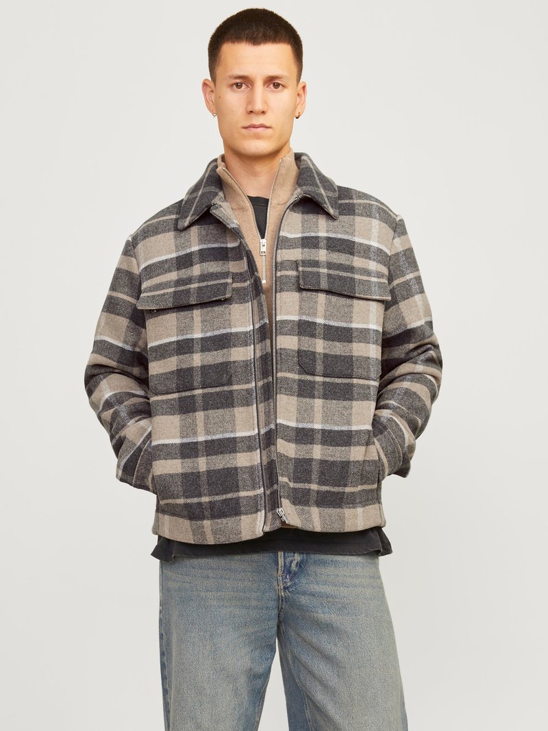 Tinklinė striukė, su pilkos ir bežinės spalvų deriniu, su užtrauktuku, dviem krūtinės kišenėmis ir apykaklės dizainu. Minkšta tekstilė.