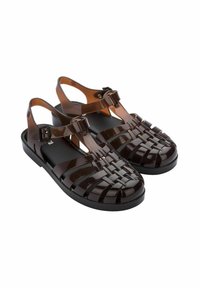 Czarne, błyszczące plastikowe sandały z plecionym wzorem, regulowanym paskiem na kostkę i płaską podeszwą. Gładka faktura i nowoczesny styl.