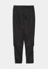 Zwarte sportieve broek met een elastische tailleband. Gemaakt van een gladde stof, met witte accenten aan de onderkant van het been en een taps toelopend ontwerp.