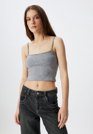 Top corto de algodón gris con tirantes finos, combinado con jeans de mezclilla negra de cintura alta que cuentan con bolsillos frontales y cierre de botón.