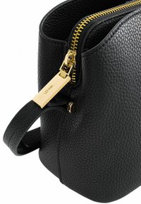 Czarna skórzana torebka o fakturowanym wykończeniu, złotym suwaku i akcentach w hardware. Uchwyt boczny ułatwiający noszenie; cylindryczny kształt.