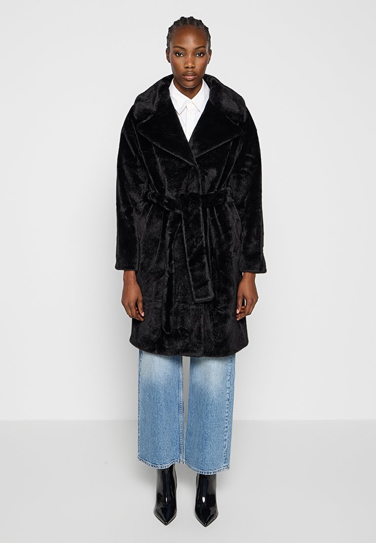 Black, faux fur coat with a wide collar and belted waist; features a soft texture and long sleeves; paired with light blue wide-leg jeans.