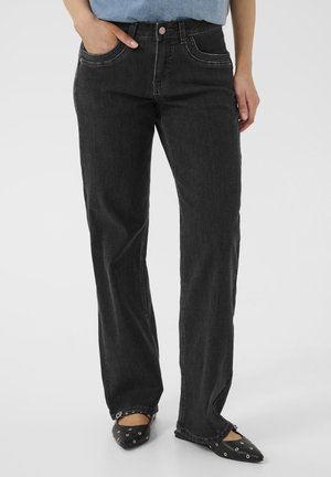 Jeans en denim noir avec une coupe droite, poches avant et détails de couture visibles. Associés à des ballerines noires pointues.