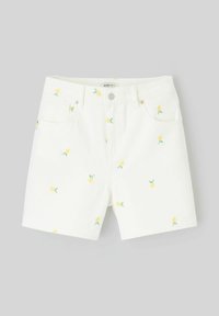 Shorts en denim blanc avec broderie de ananas jaune et feuilles vertes, dotés de poches avant et d'une fermeture à bouton.
