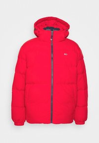 Veste matelassée rouge avec capuche, fermeture éclair frontale, poignets élastiques, poches latérales et petit logo sur la poitrine gauche sur un fond uni.